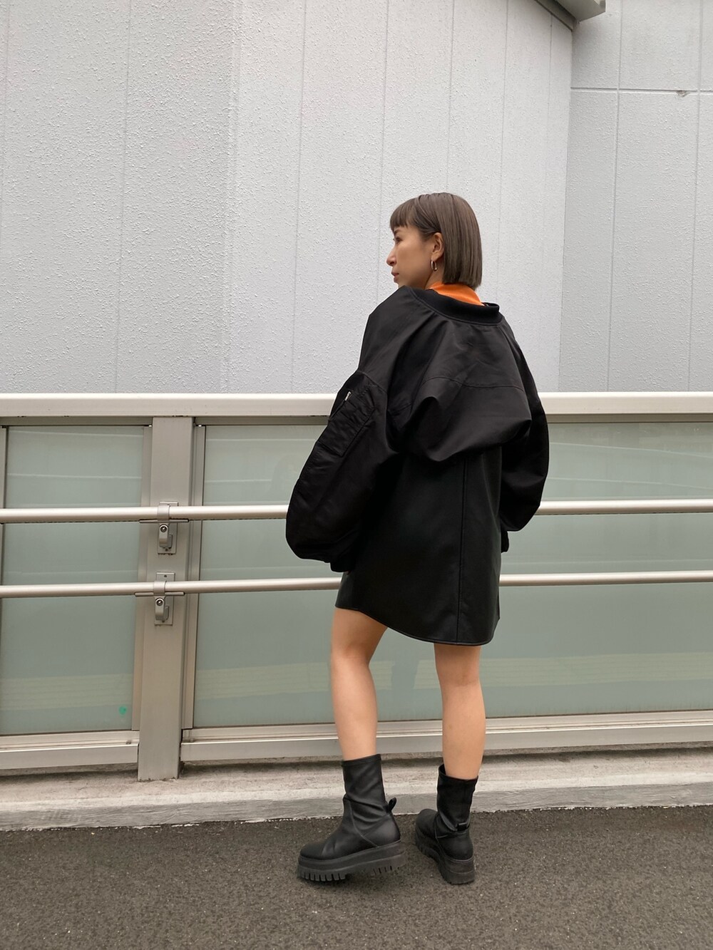 ブラック系のワンピース、ブラック系のMA-1、オレンジ系のニット/セーターを着用したレディースの冬コーディネートの2枚目の写真