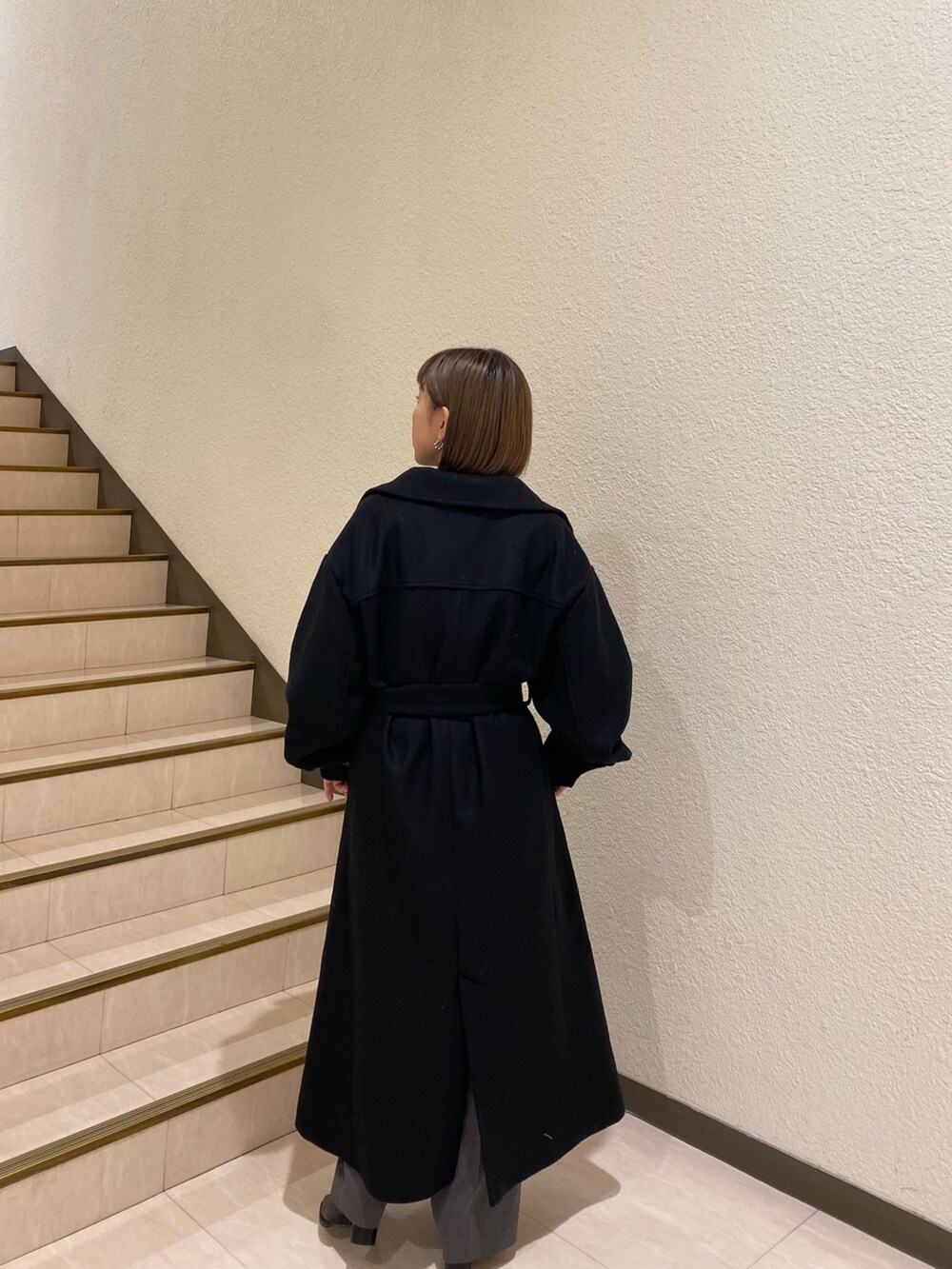 ブラック系のダウンジャケット/コート、パープル系のニット/セーター、グレー系のスラックスを着用したレディースの秋コーディネートの4枚目の写真