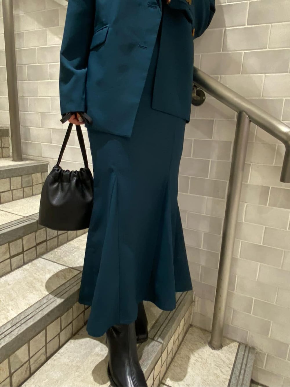 ブラック系のタンクトップ、グリーン系のテーラードジャケット、グリーン系のスカートを着用したレディースの夏コーディネートの7枚目の写真