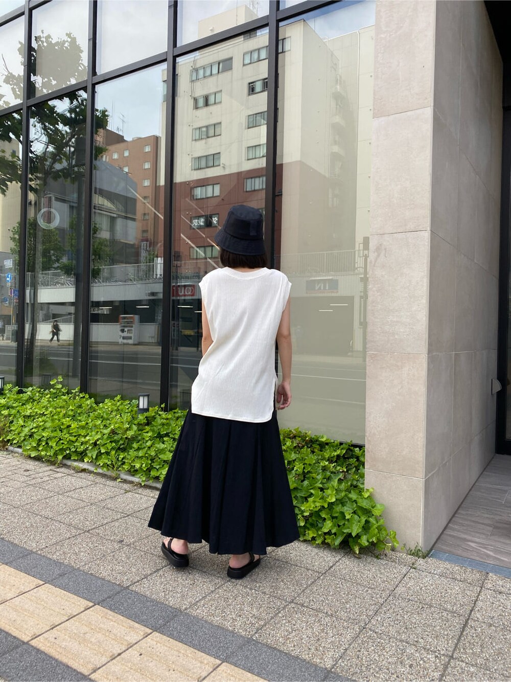 ブラック系のスカート、ブラック系のサンダル、ホワイト系のTシャツ/カットソーを着用したレディースの夏コーディネートの3枚目の写真