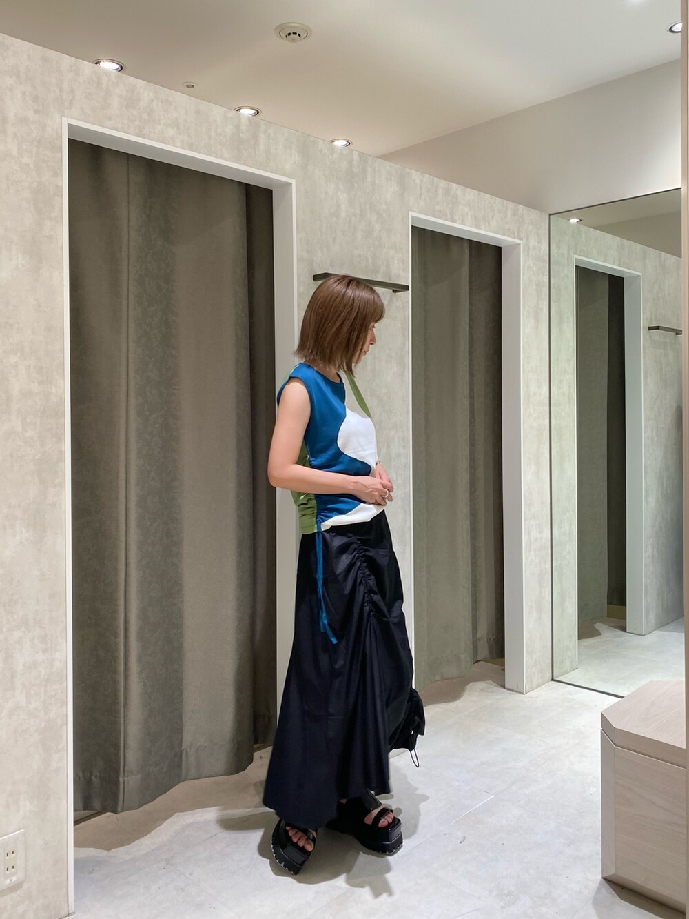 ブルー系のニット/セーター、ブラック系のスカート、ブラック系のサンダルを着用したレディースの夏コーディネートの3枚目の写真