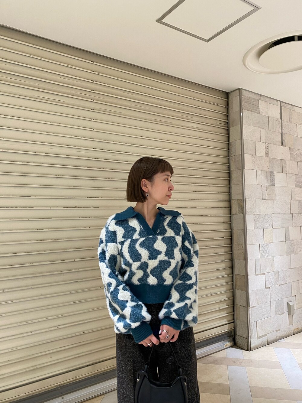 グリーン系のニット/セーター、ブラック系のスラックス、ブラック系のブーツを着用したレディースの秋コーディネートの5枚目の写真