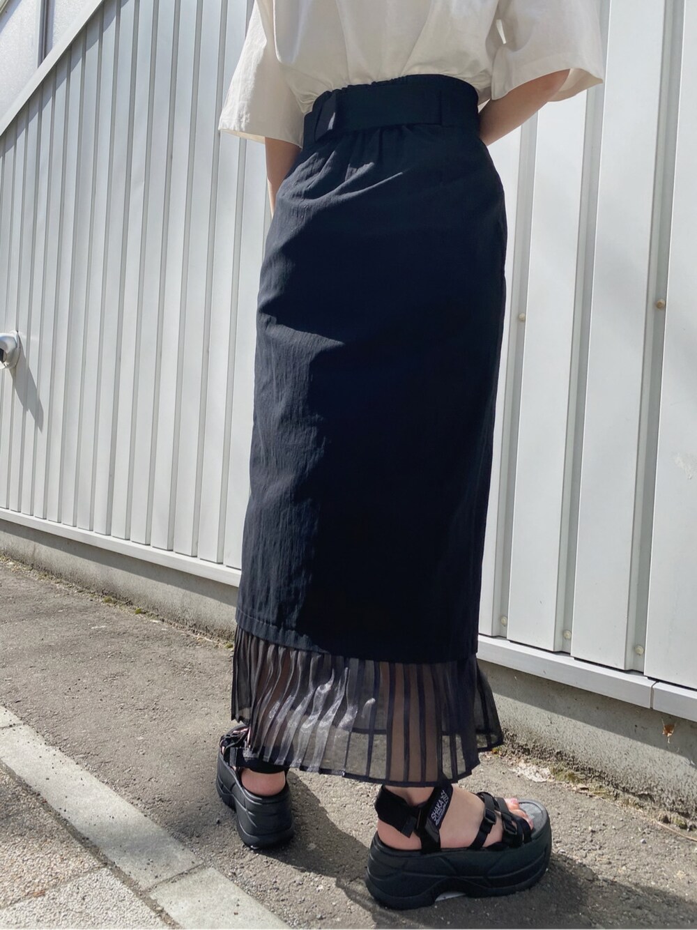 ブラック系のスカート、ホワイト系のTシャツ/カットソー、ブラック系のハンドバッグを着用したレディースの春コーディネートの6枚目の写真