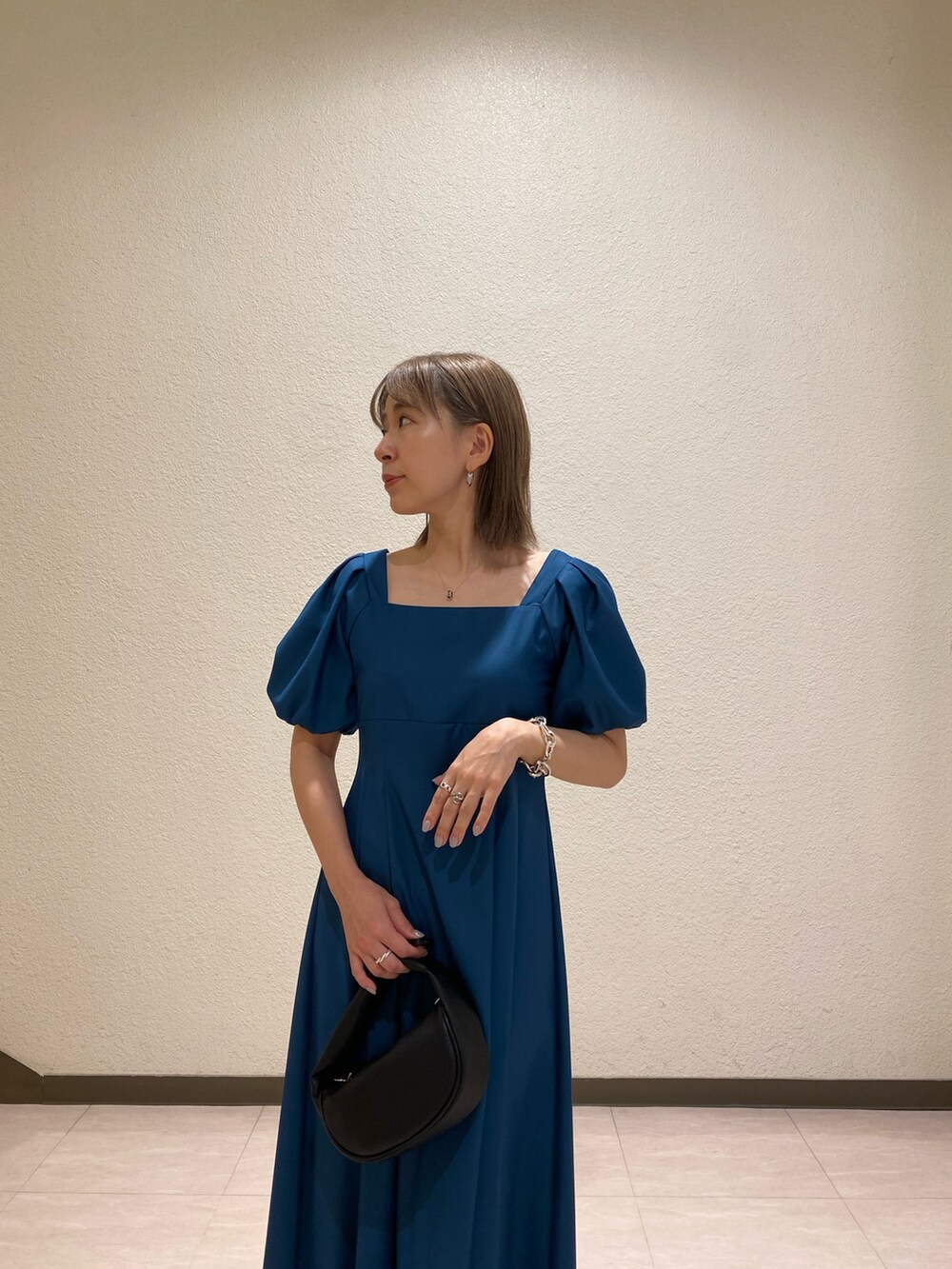 ブルー系のワンピース、ブラック系のサンダル、ブラック系のハンドバッグを着用したレディースの夏コーディネートの5枚目の写真