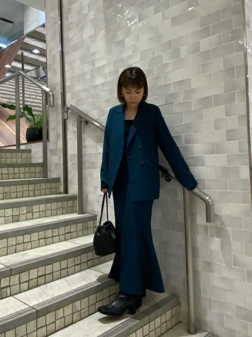 ブラック系のタンクトップ、グリーン系のテーラードジャケット、グリーン系のスカートを着用したレディースの夏コーディネートの2枚目の写真