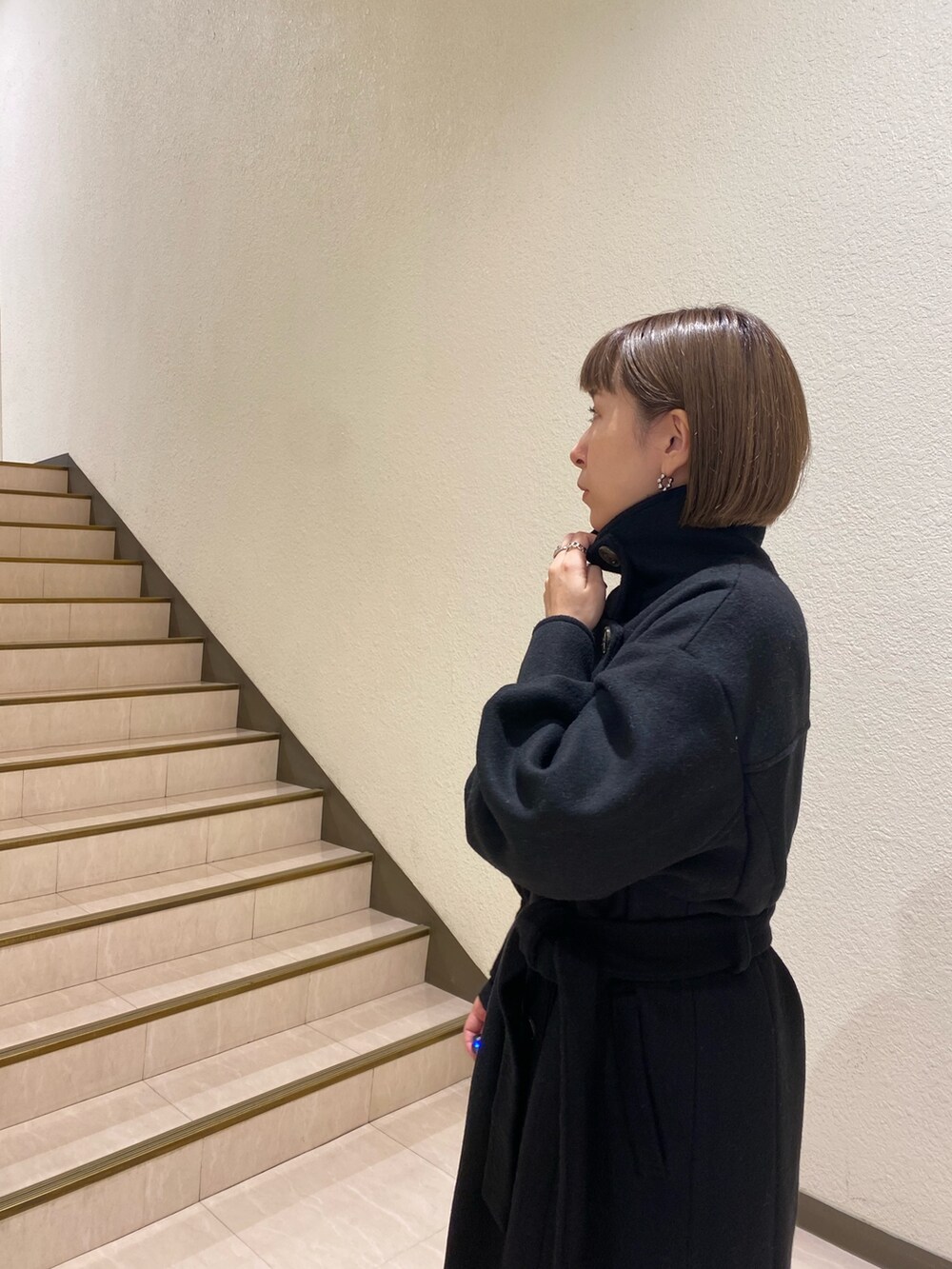 ブラック系のダウンジャケット/コート、パープル系のニット/セーター、グレー系のスラックスを着用したレディースの秋コーディネートの9枚目の写真