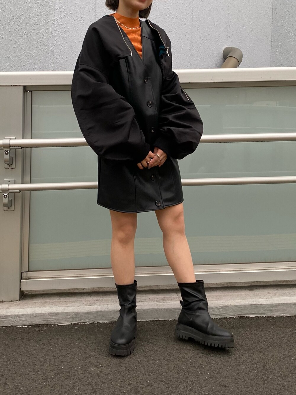 ブラック系のワンピース、ブラック系のMA-1、オレンジ系のニット/セーターを着用したレディースの冬コーディネートの3枚目の写真