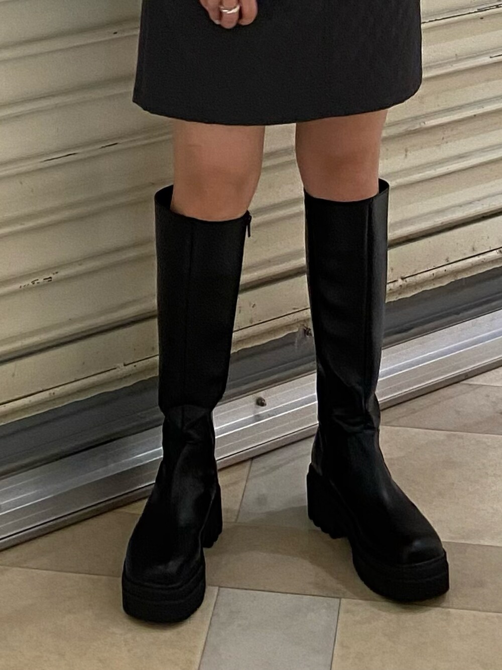 パープル系のニット/セーター、グレー系のスカート、ブラック系のブーツを着用したレディースの秋コーディネートの7枚目の写真