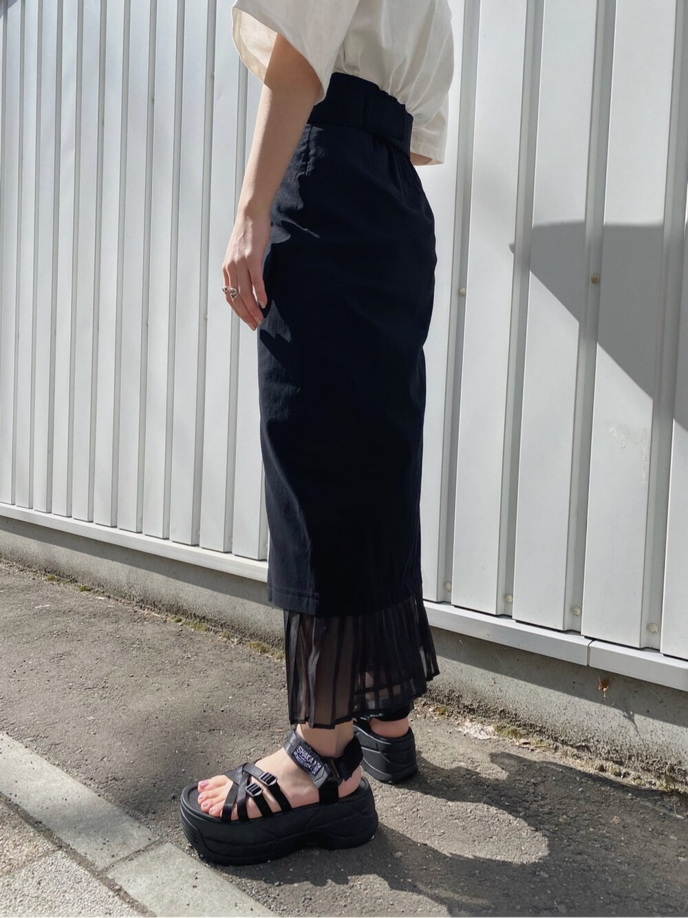 ブラック系のスカート、ホワイト系のTシャツ/カットソー、ブラック系のハンドバッグを着用したレディースの春コーディネートの5枚目の写真