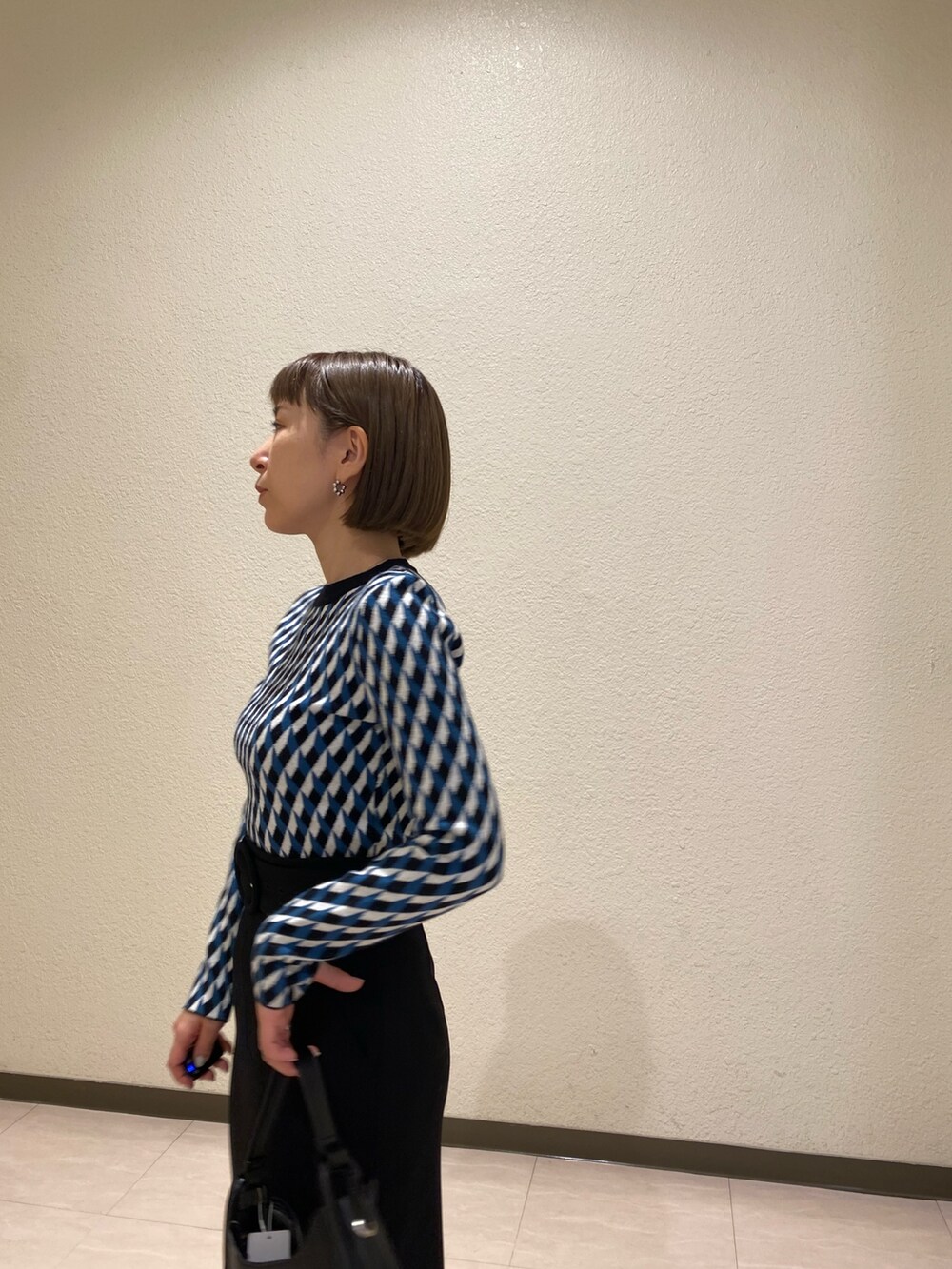 ブラック系のニット/セーター、ブラック系のスカート、ブラック系のブーツを着用したレディースの秋コーディネートの5枚目の写真