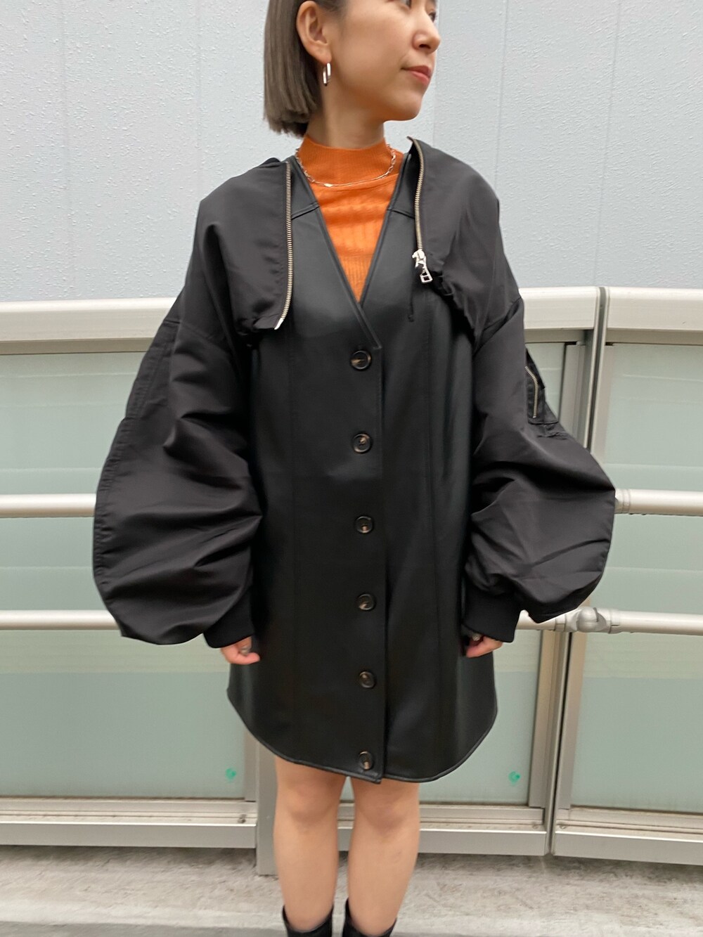 ブラック系のワンピース、ブラック系のMA-1、オレンジ系のニット/セーターを着用したレディースの冬コーディネートの8枚目の写真