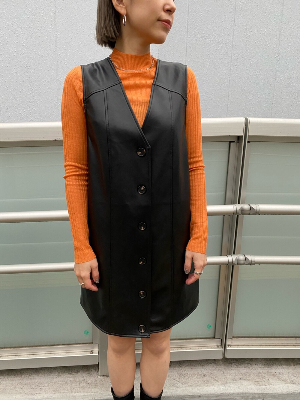 ブラック系のワンピース、ブラック系のMA-1、オレンジ系のニット/セーターを着用したレディースの冬コーディネートの6枚目の写真