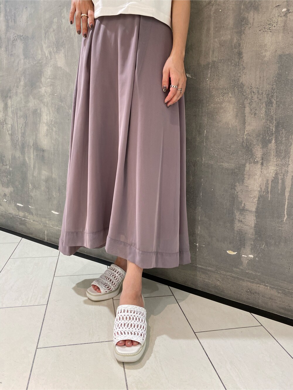 パープル系のスカート、ホワイト系のサンダル、ホワイト系のタンクトップを着用したレディースの夏コーディネートの3枚目の写真