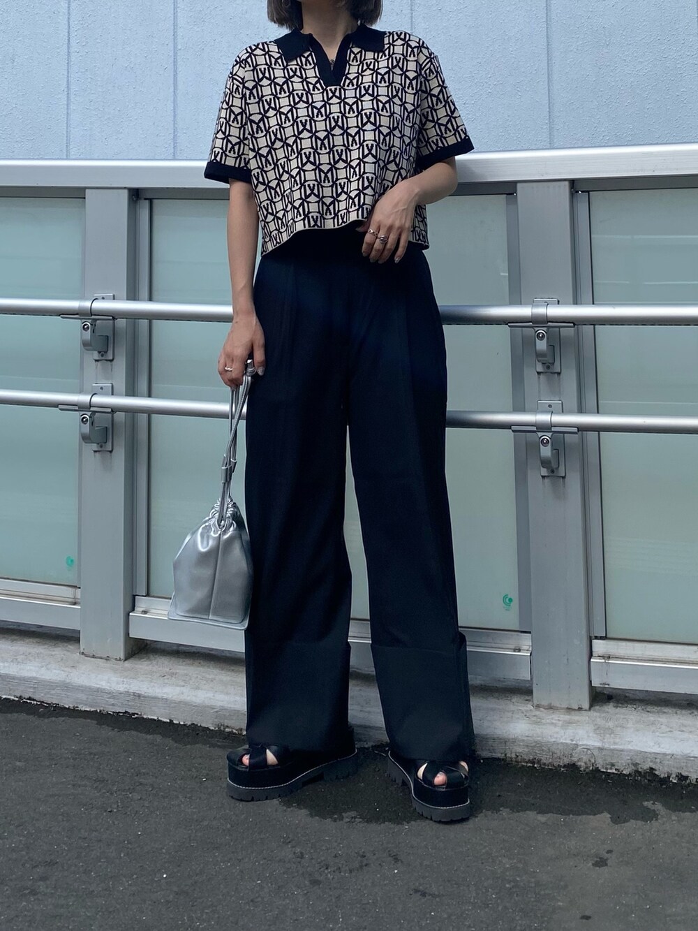 ブラック系のポロシャツ、グレー系のスラックス、ブラック系のサンダルを着用したレディースの春コーディネートの3枚目の写真