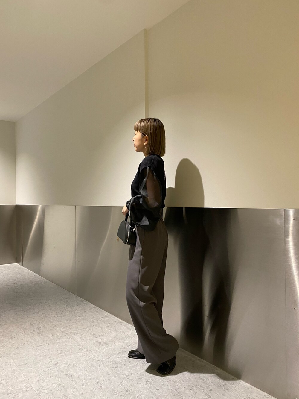 ブラック系のニット/セーター、グレー系のスラックスを着用したレディースの冬コーディネートの3枚目の写真