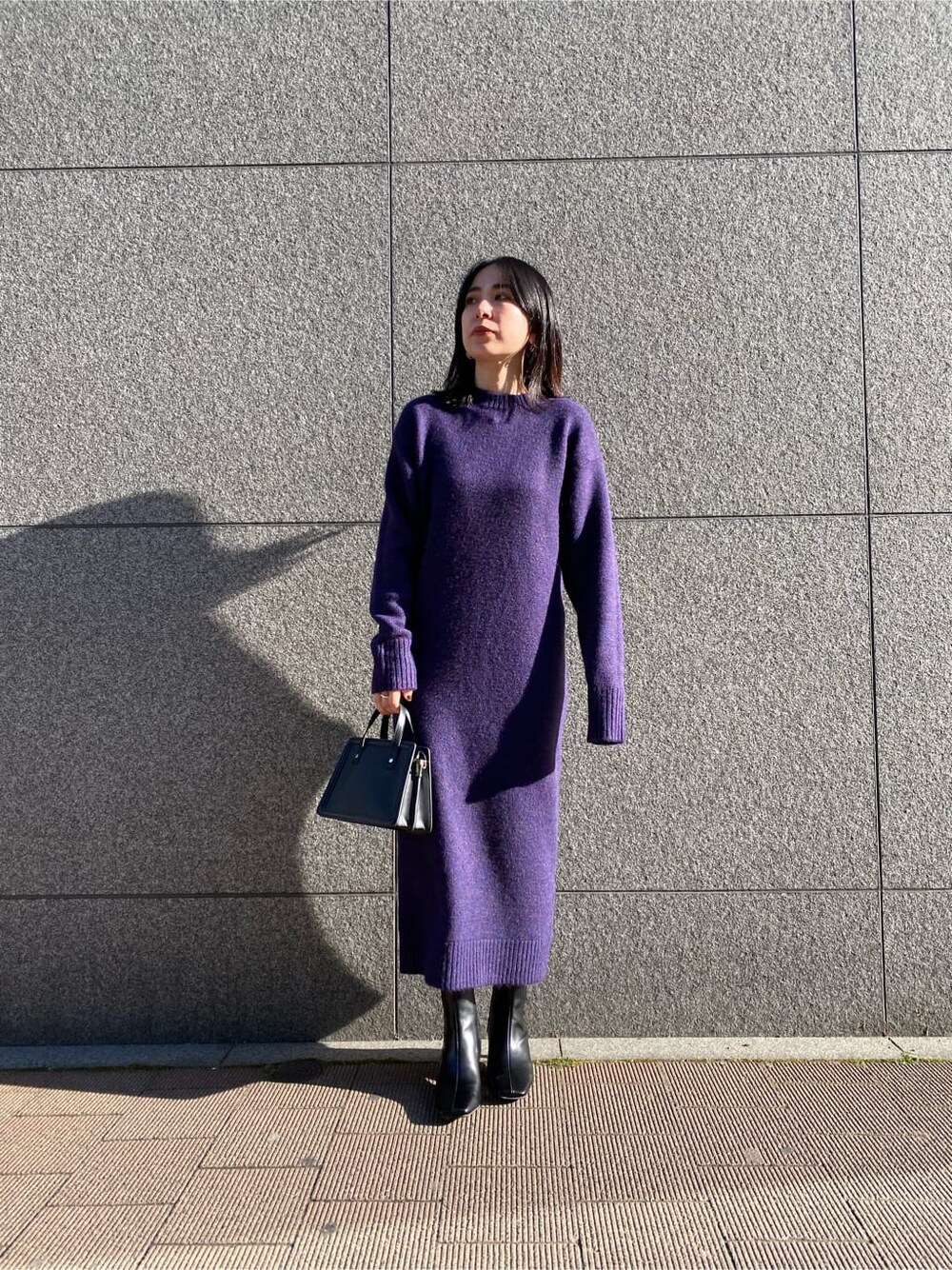 ブラック系のハンドバッグ、パープル系のワンピース、ブラック系のブーツを着用したレディースの冬コーディネートの5枚目の写真