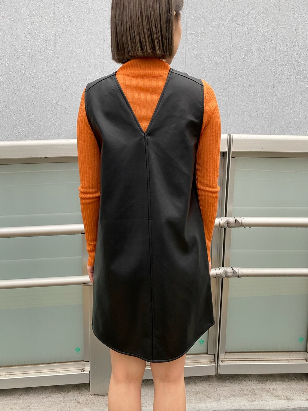 ブラック系のワンピース、ブラック系のMA-1、オレンジ系のニット/セーターを着用したレディースの冬コーディネートの7枚目の写真