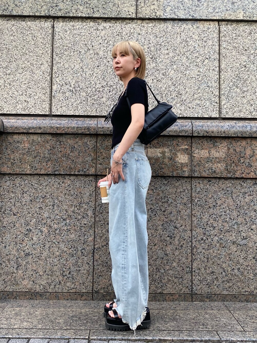 ブルー系のデニムパンツ、ブラック系のニット/セーター、ブラック系のハンドバッグを着用したレディースの夏コーディネートの2枚目の写真