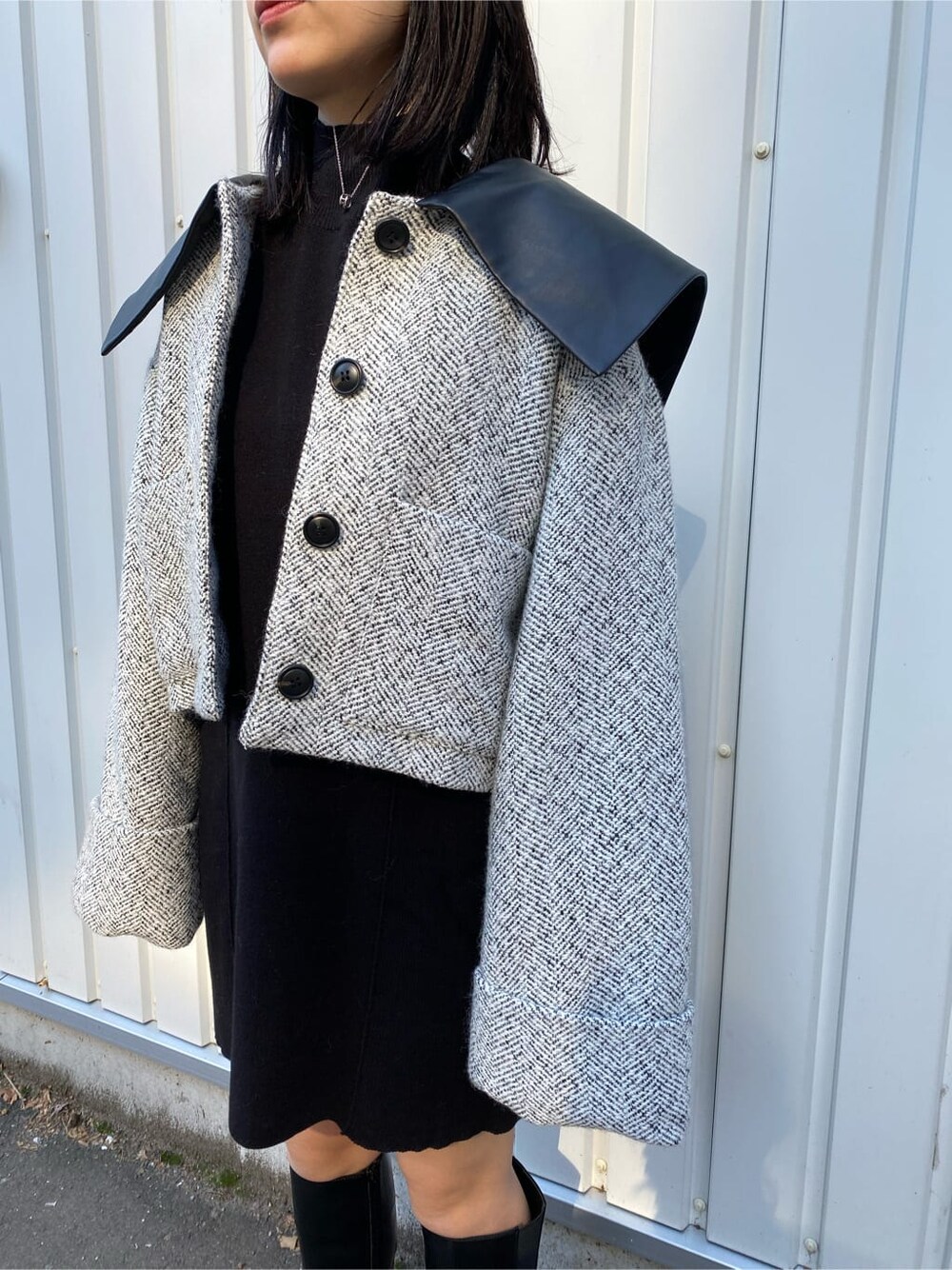 ブラック系のワンピース、ホワイト系のブルゾン、ブラック系のブーツを着用したレディースの秋コーディネートの5枚目の写真