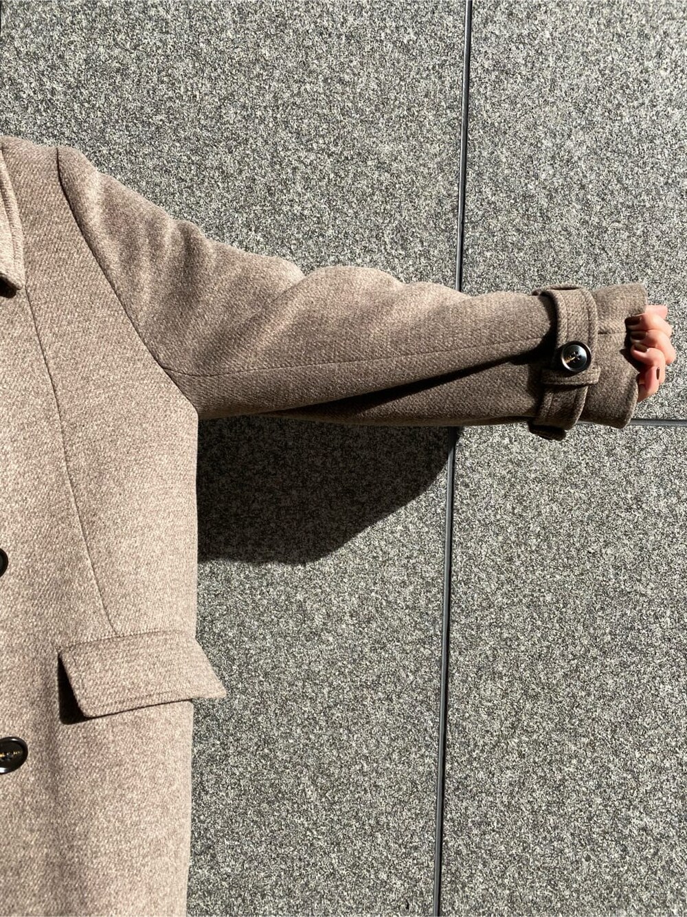 ブラック系のスラックス、ベージュ系のチェスターコート、ブラック系のブーツを着用したレディースの秋コーディネートの6枚目の写真