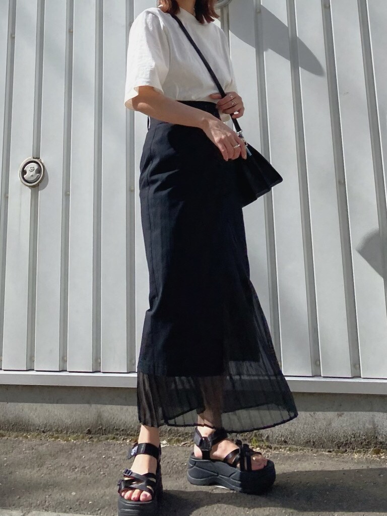 ブラック系のスカート、ホワイト系のTシャツ/カットソー、ブラック系のハンドバッグを着用したレディースの春コーディネートの3枚目の写真