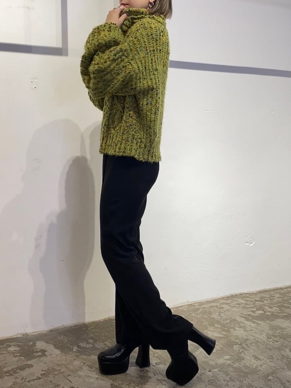 グリーン系のニット/セーター、ブラック系のスウェットパンツ、ブラック系のブーツを着用したレディースの冬コーディネートの3枚目の写真