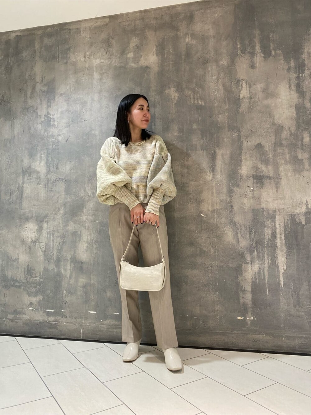 ホワイト系のブーツ、ホワイト系のスラックス、ホワイト系のニット/セーターを着用したレディースの冬コーディネートの2枚目の写真