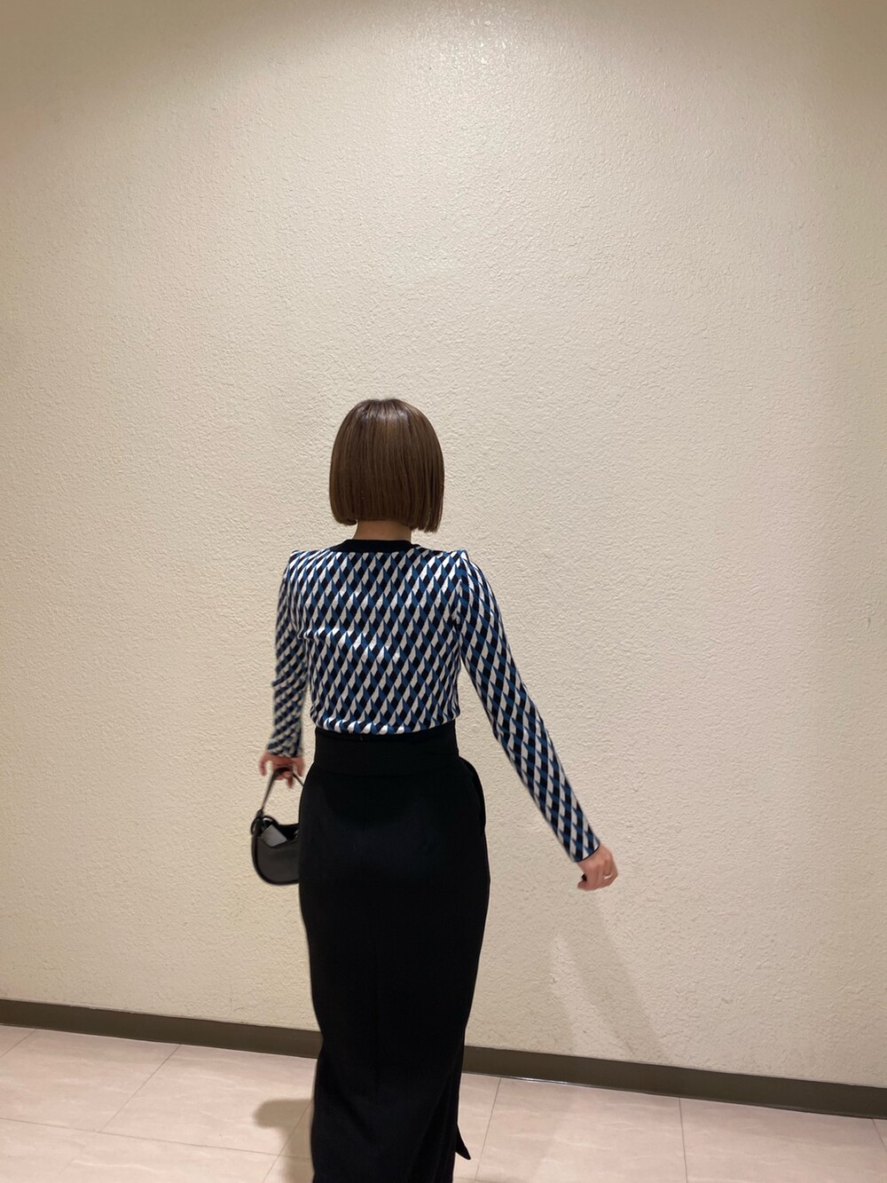 ブラック系のニット/セーター、ブラック系のスカート、ブラック系のブーツを着用したレディースの秋コーディネートの6枚目の写真