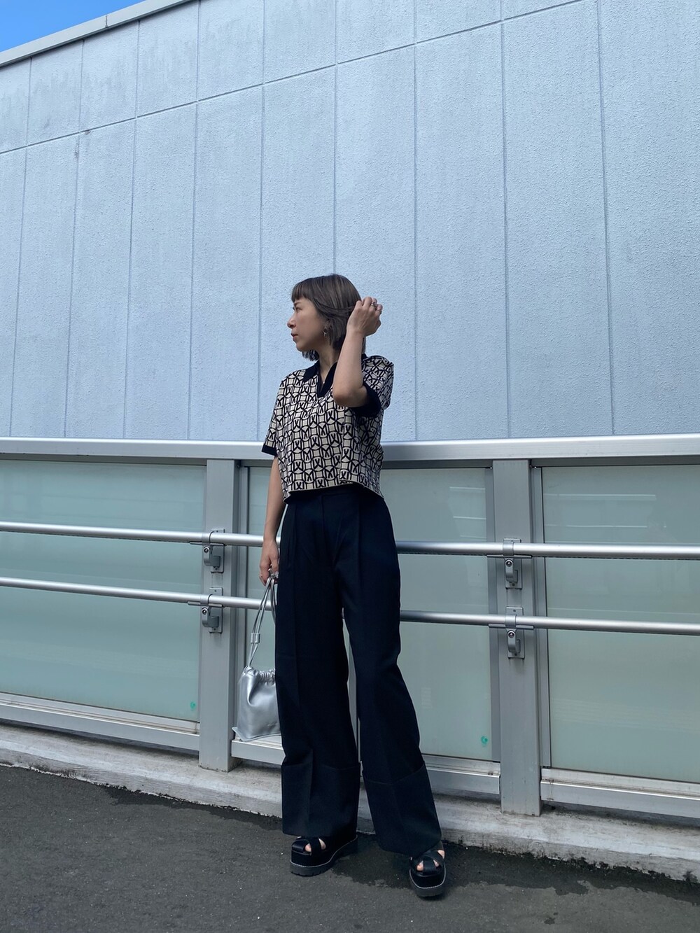 ブラック系のポロシャツ、グレー系のスラックス、ブラック系のサンダルを着用したレディースの春コーディネートの2枚目の写真