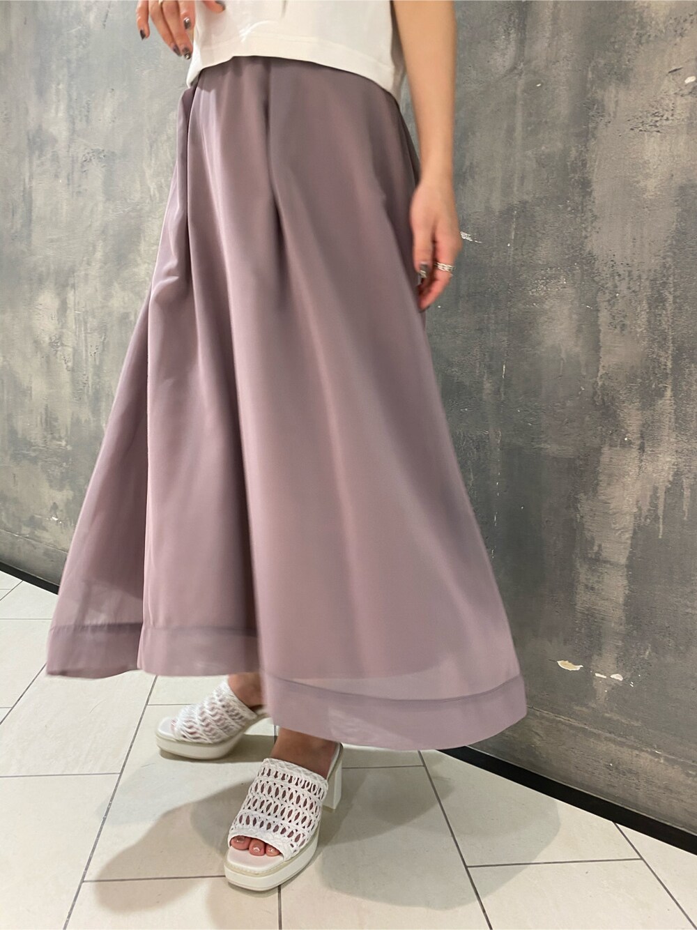 パープル系のスカート、ホワイト系のサンダル、ホワイト系のタンクトップを着用したレディースの夏コーディネートの6枚目の写真