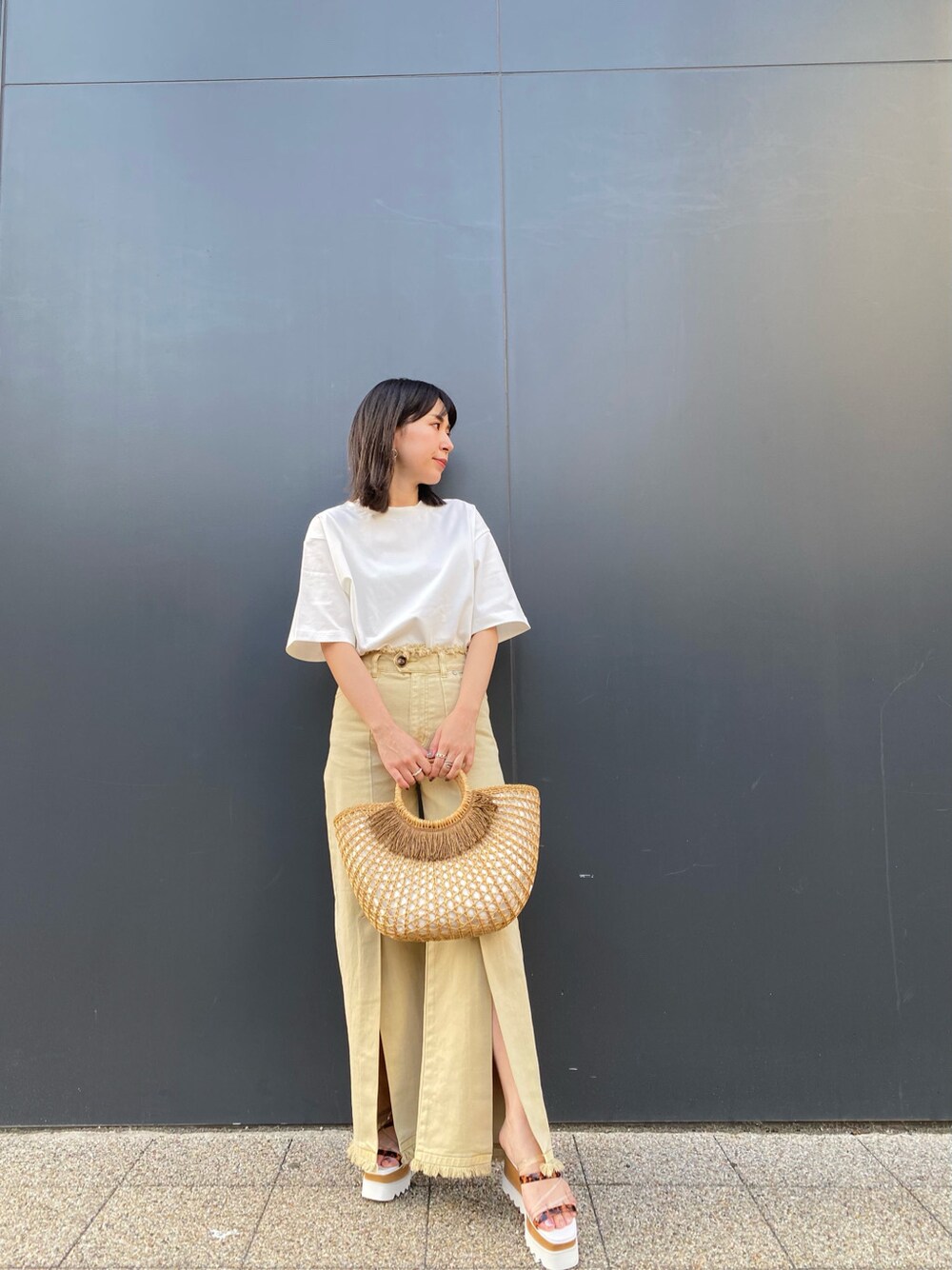 ベージュ系のかごバッグ、イエロー系のその他パンツ、ホワイト系のTシャツ/カットソーを着用したレディースの春コーディネートの4枚目の写真
