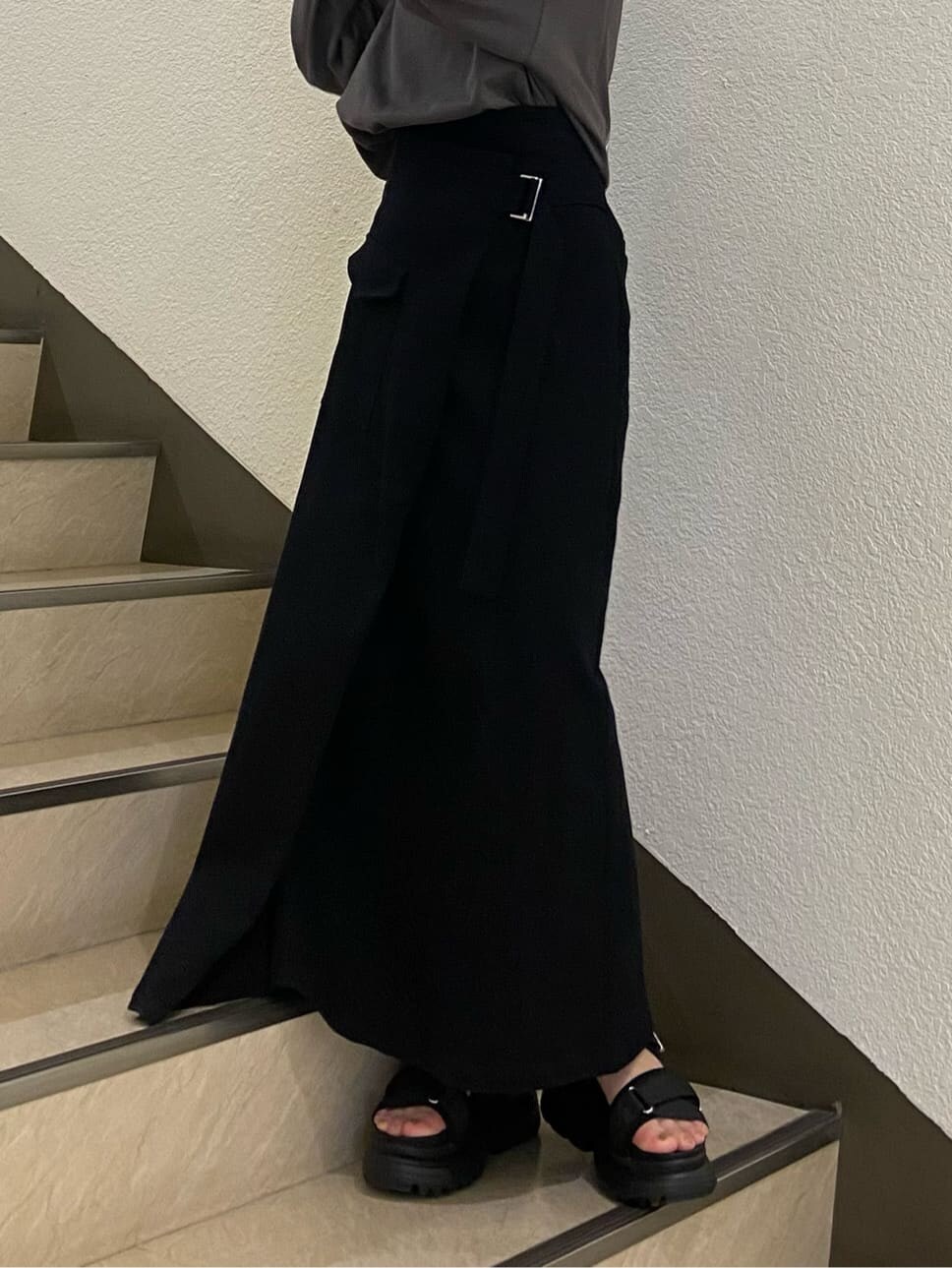 ブラック系のスカート、ブラック系のサンダル、グレー系のTシャツ/カットソーを着用したレディースの春コーディネートの6枚目の写真