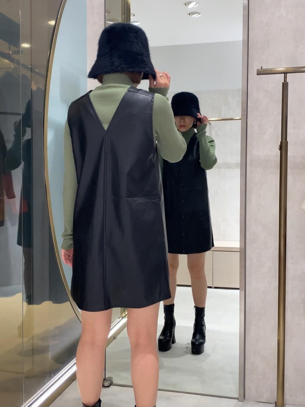 ブラック系のブーツ、ブラック系のワンピース、グリーン系のニット/セーターを着用したレディースの秋コーディネートの4枚目の写真