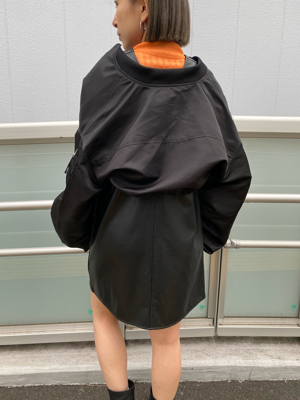 ブラック系のワンピース、ブラック系のMA-1、オレンジ系のニット/セーターを着用したレディースの冬コーディネートの9枚目の写真