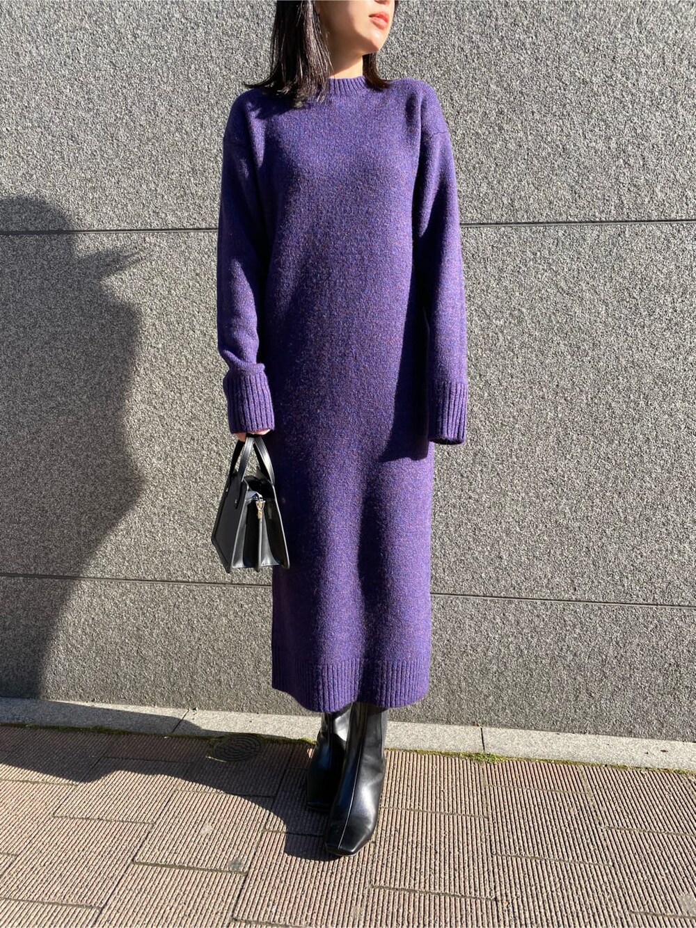 ブラック系のハンドバッグ、パープル系のワンピース、ブラック系のブーツを着用したレディースの冬コーディネートの7枚目の写真