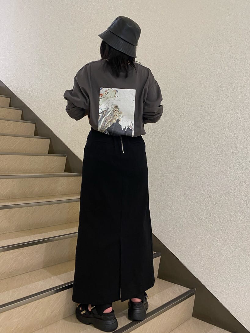 ブラック系のスカート、ブラック系のサンダル、グレー系のTシャツ/カットソーを着用したレディースの春コーディネートの2枚目の写真