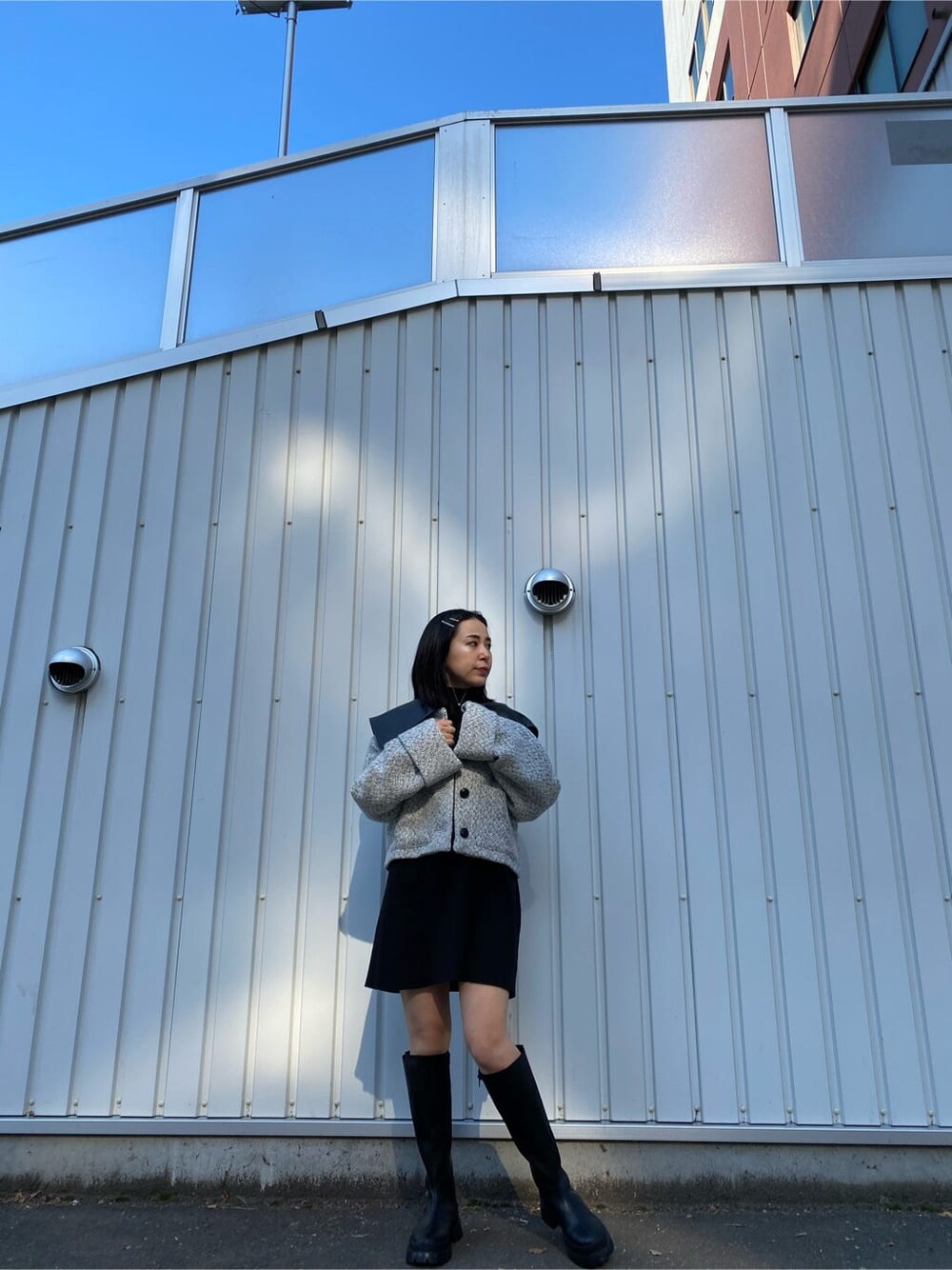 ブラック系のワンピース、ホワイト系のブルゾン、ブラック系のブーツを着用したレディースの秋コーディネートの2枚目の写真