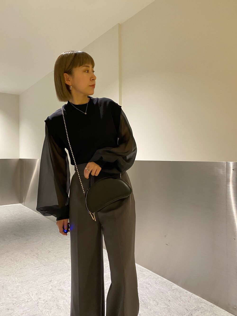 ブラック系のニット/セーター、グレー系のスラックスを着用したレディースの冬コーディネートの5枚目の写真