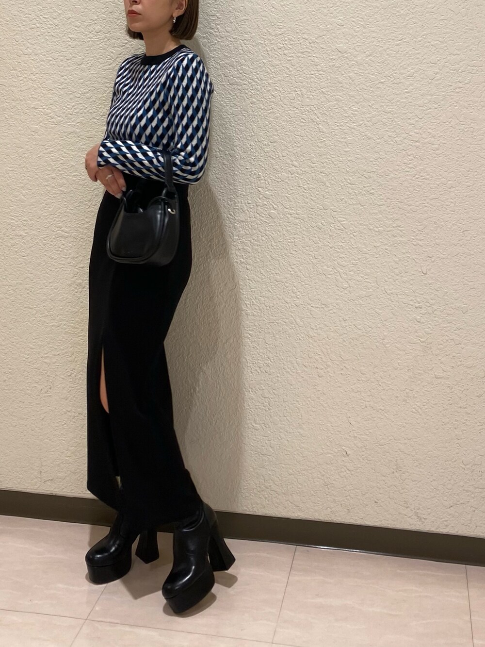 ブラック系のニット/セーター、ブラック系のスカート、ブラック系のブーツを着用したレディースの秋コーディネートの4枚目の写真