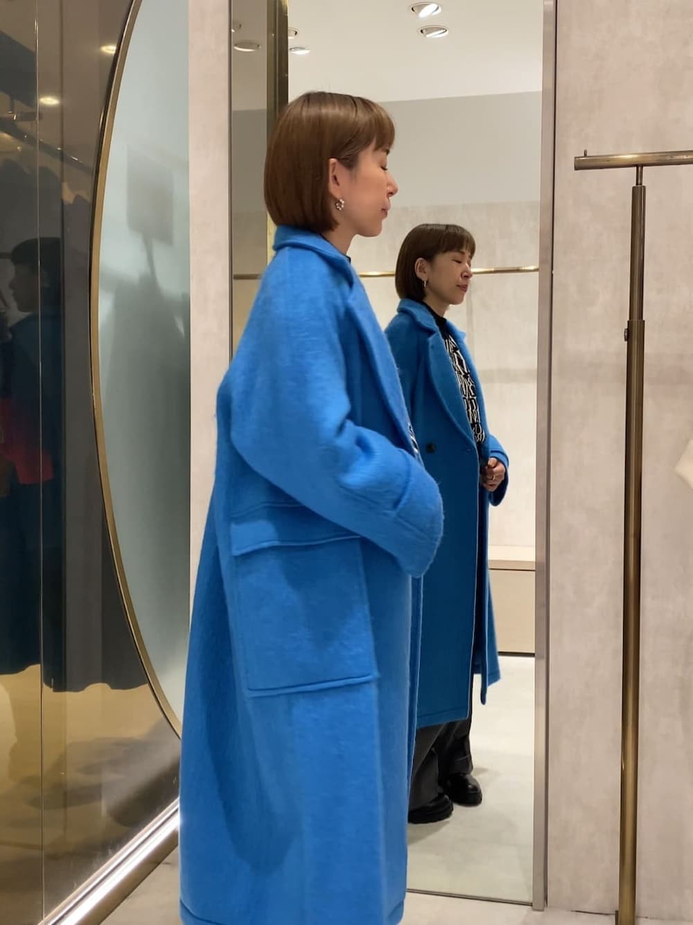 ブラック系のブーツ、ブルー系のチェスターコート、ブラック系のニット/セーターを着用したレディースの秋コーディネートの2枚目の写真