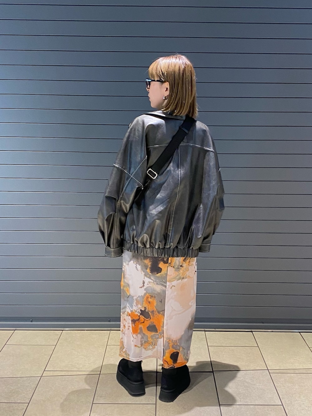 グレー系のブルゾン、オレンジ系のワンピースを着用したレディースの春コーディネートの2枚目の写真