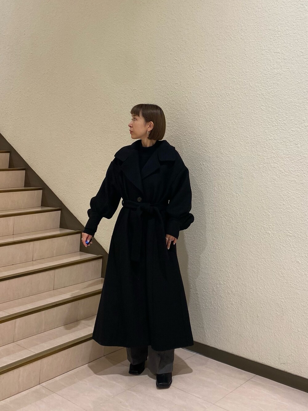 ブラック系のダウンジャケット/コート、パープル系のニット/セーター、グレー系のスラックスを着用したレディースの秋コーディネートの2枚目の写真