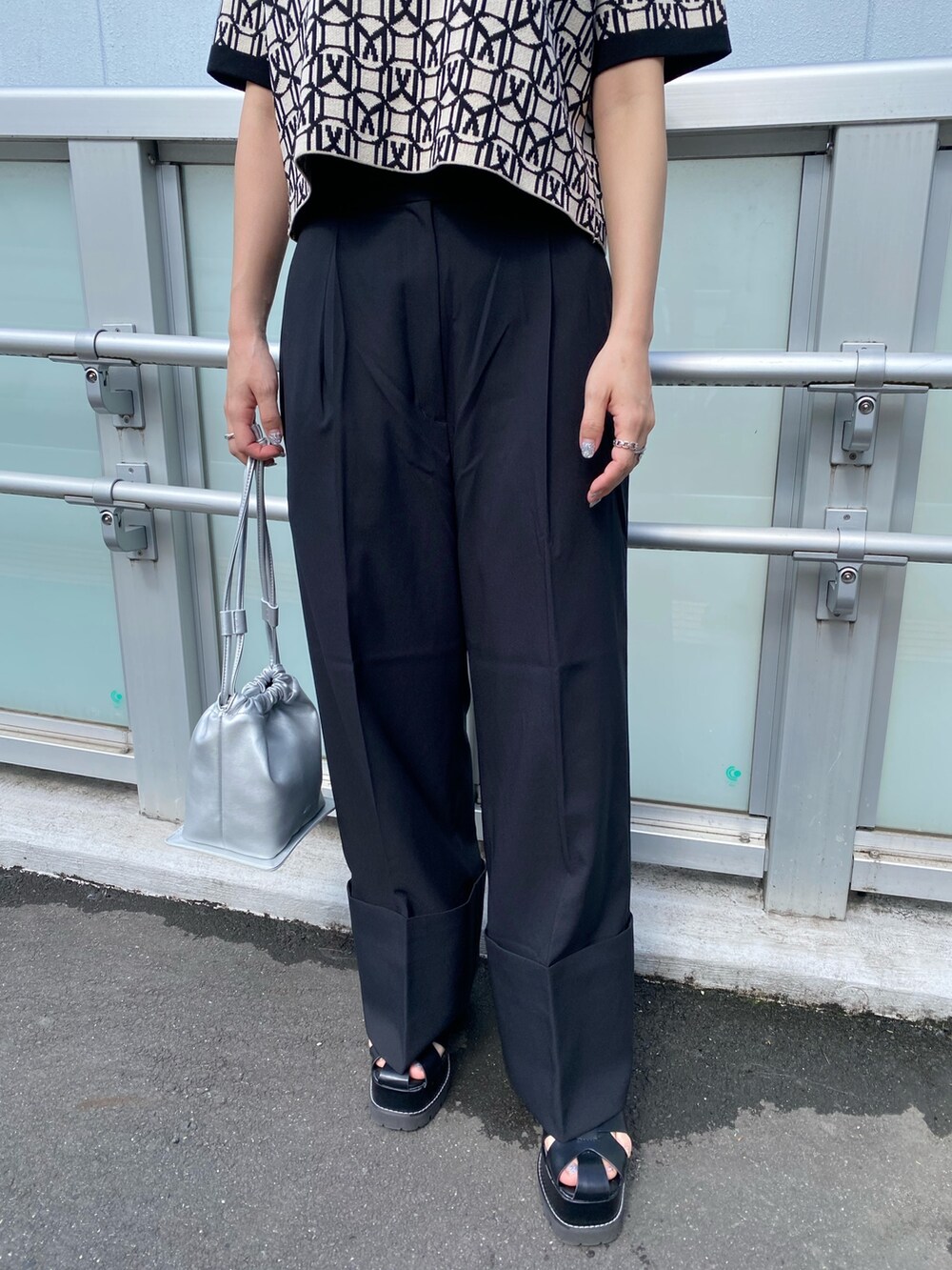 ブラック系のポロシャツ、グレー系のスラックス、ブラック系のサンダルを着用したレディースの春コーディネートの7枚目の写真