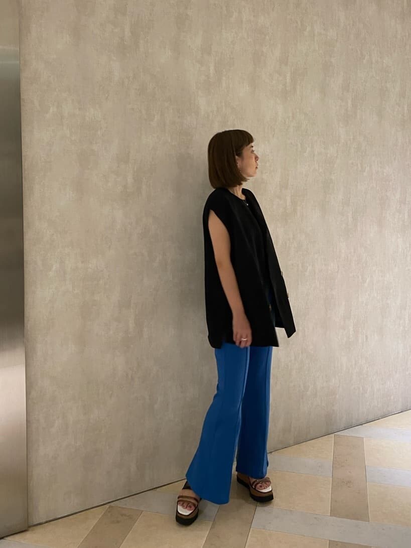 ブルー系のスラックス、ブラック系のベスト、ブラック系のタンクトップを着用したレディースの夏コーディネートの4枚目の写真