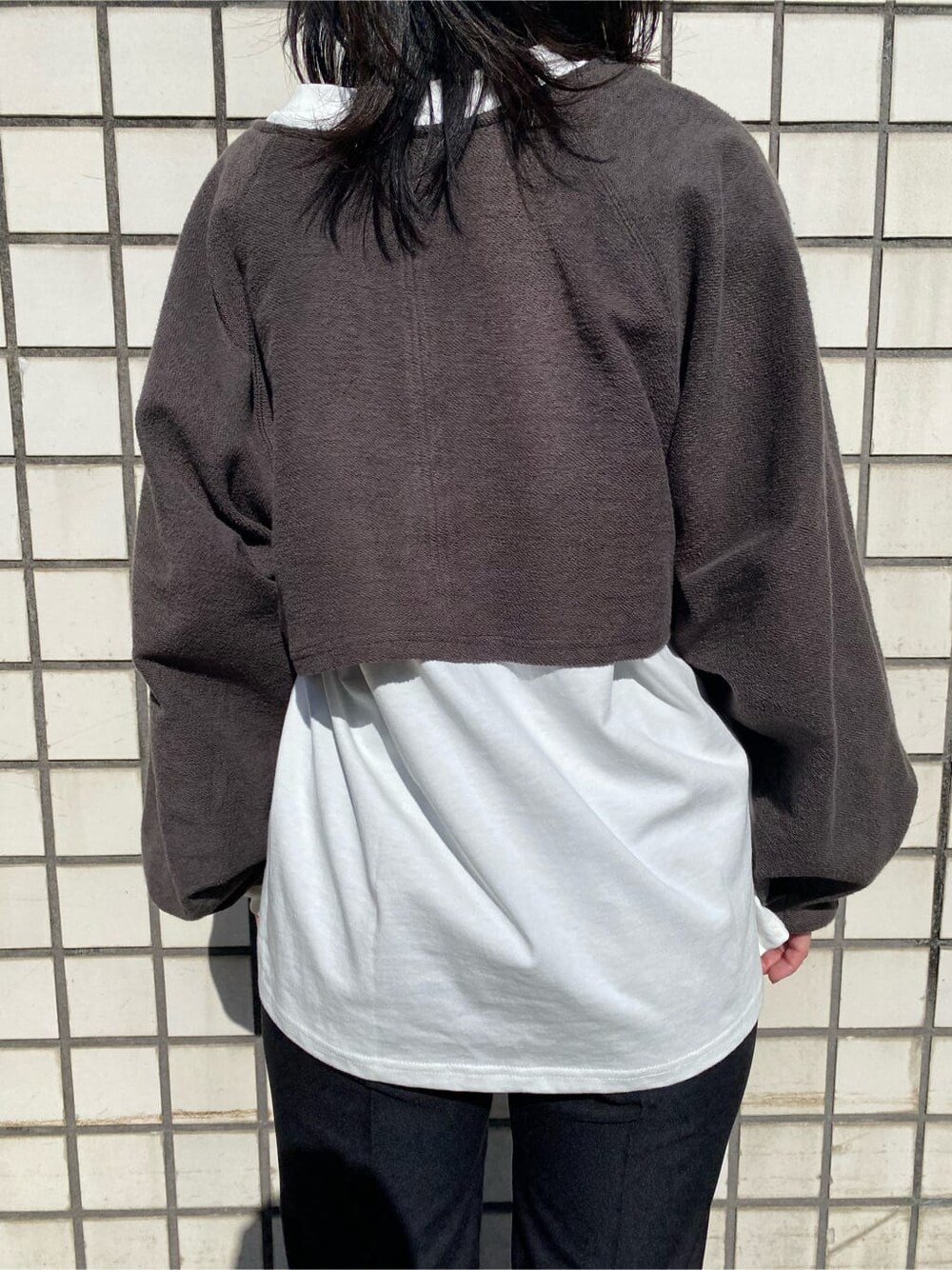 ブラック系のハンドバッグ、ブラック系のスラックス、ブラック系のブーツを着用したレディースの冬コーディネートの6枚目の写真