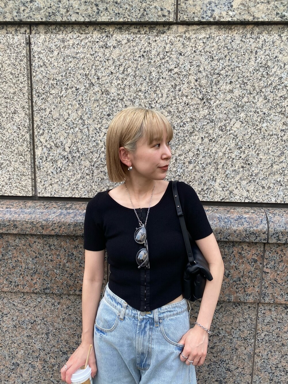 ブルー系のデニムパンツ、ブラック系のニット/セーター、ブラック系のハンドバッグを着用したレディースの夏コーディネートの4枚目の写真