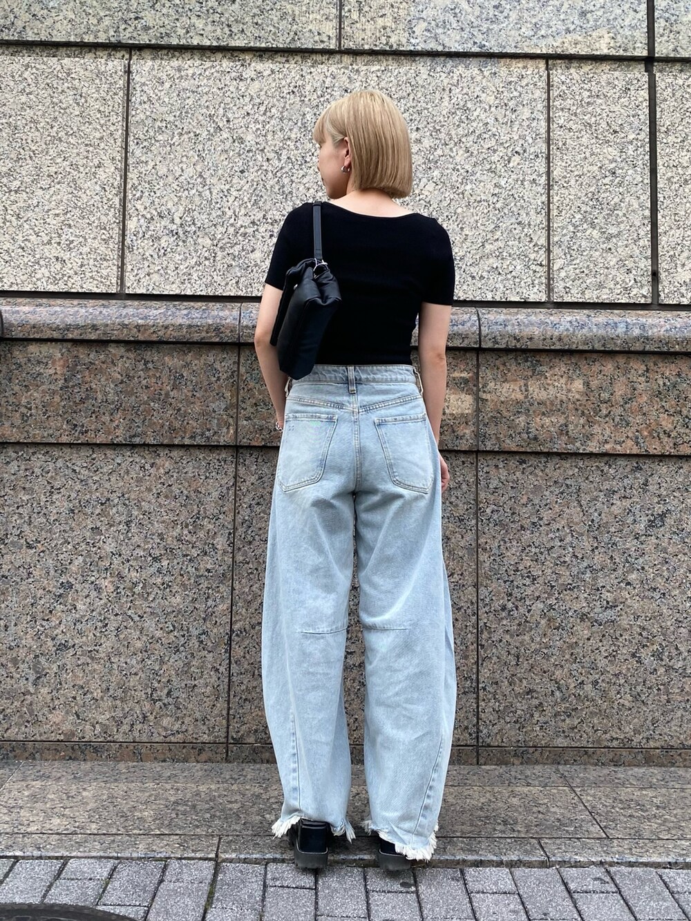 ブルー系のデニムパンツ、ブラック系のニット/セーター、ブラック系のハンドバッグを着用したレディースの夏コーディネートの3枚目の写真