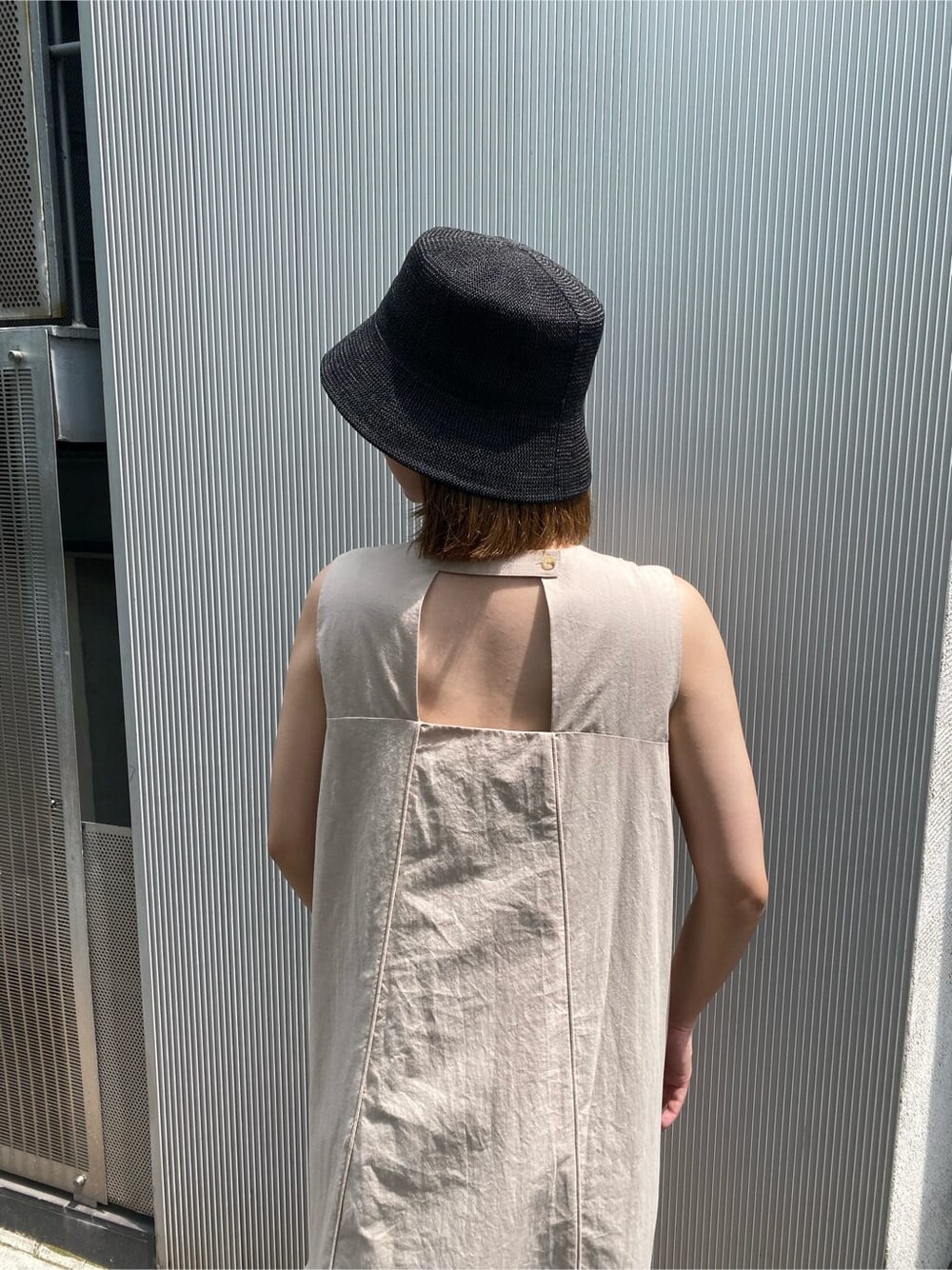 ベージュ系のワンピース、ブラック系のハットを着用したレディースの夏コーディネートの4枚目の写真