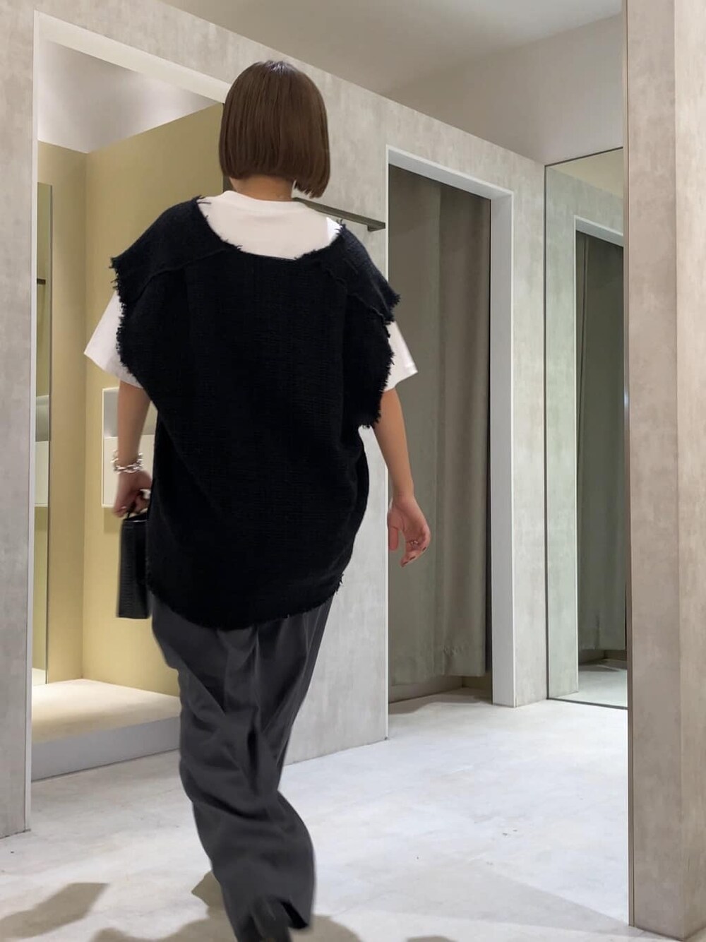 グレー系のスラックス、ブラック系のブーツ、ブラック系のワンピースを着用したレディースの夏コーディネートの4枚目の写真