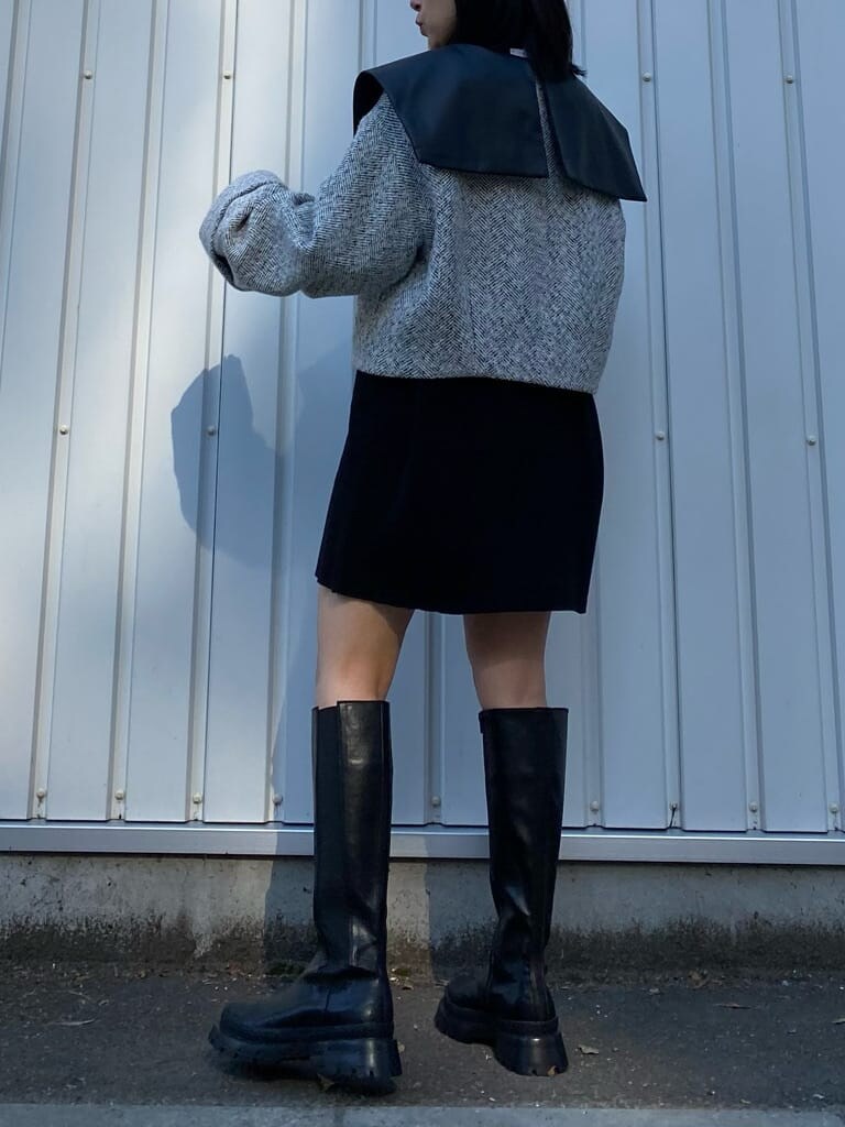 ブラック系のワンピース、ホワイト系のブルゾン、ブラック系のブーツを着用したレディースの秋コーディネートの4枚目の写真